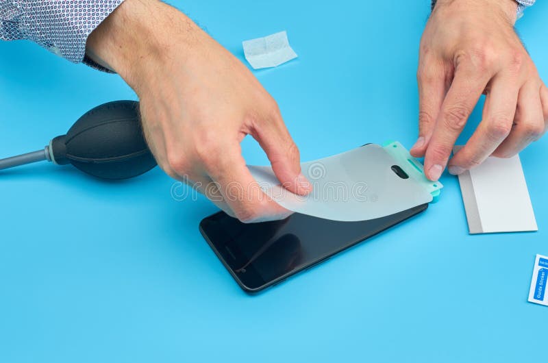 L'homme remplaçant le protecteur cassé d'écran de verre trempé pour le smartphone photo stock L'homme remplaçant le protecteur cassé d'écran de verre trempé pour le smartphone photo stock