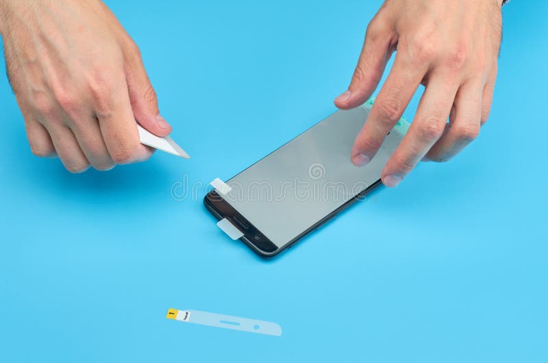 L'homme remplaçant le protecteur cassé d'écran de verre trempé pour le smartphone photographie stock L'homme remplaçant le protecteur cassé d'écran de verre trempé pour le smartphone photographie stock