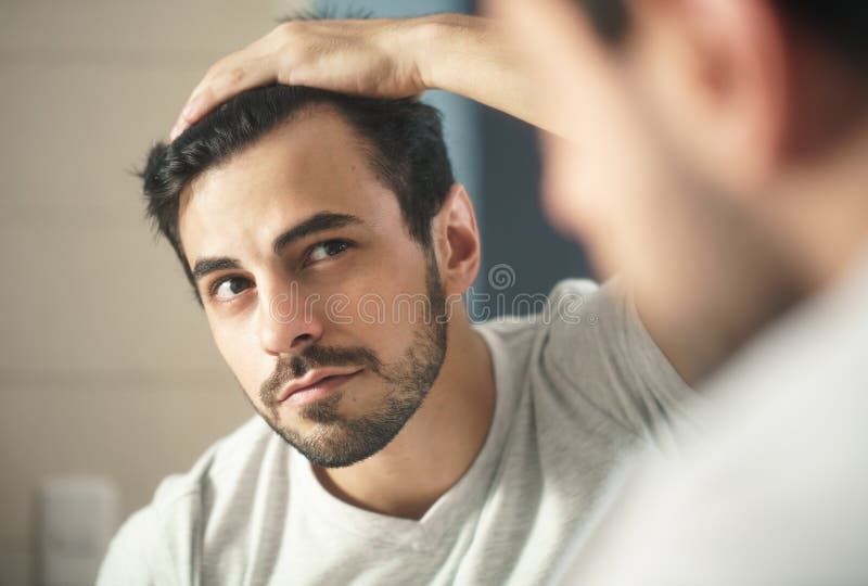 L'homme s'est inquiété pour l'alopécie examinant des cheveux pour assurer la perte