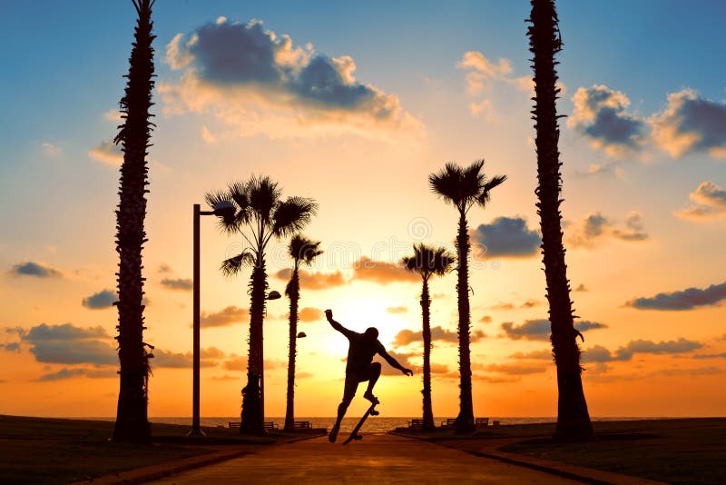 L'homme sautant sur la planche à roulettes dans le coucher du soleil photo libre de droits L'homme sautant sur la planche à roulettes dans le coucher du soleil photo libre de droits