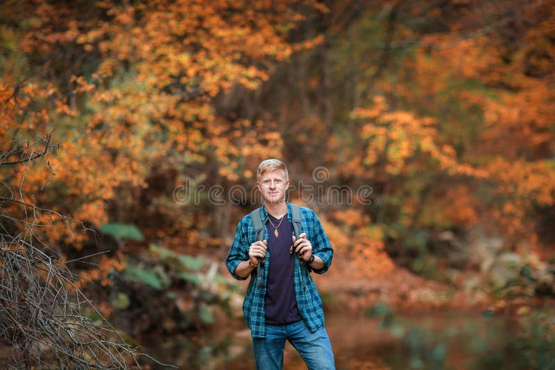 L'homme se tient pr?s du courant de montagne en automne images stock L'homme se tient pr?s du courant de montagne en automne images stock