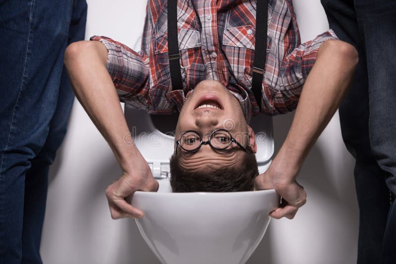 L'homme se tient à l'envers sur la cuvette des toilettes photographie stock libre de droits