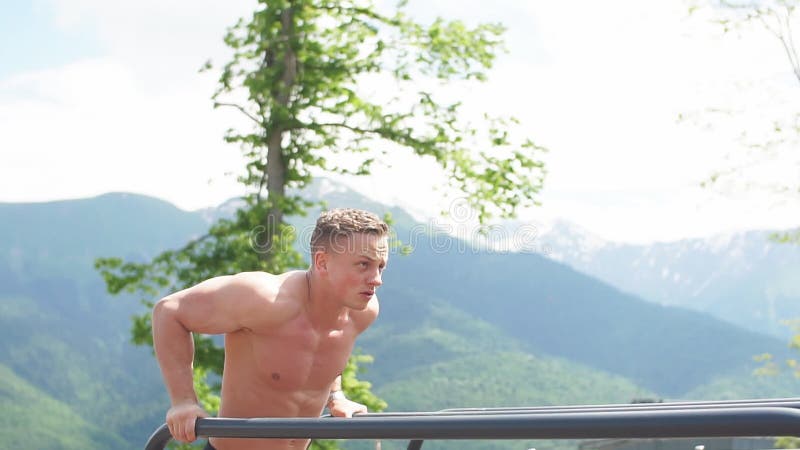 L'homme sportif motivé fait des pousées de poids du corps au gymnase extérieur de secteur de montagnes