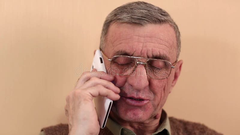 L'homme supérieur avec le smartphone blanc parle et sourit