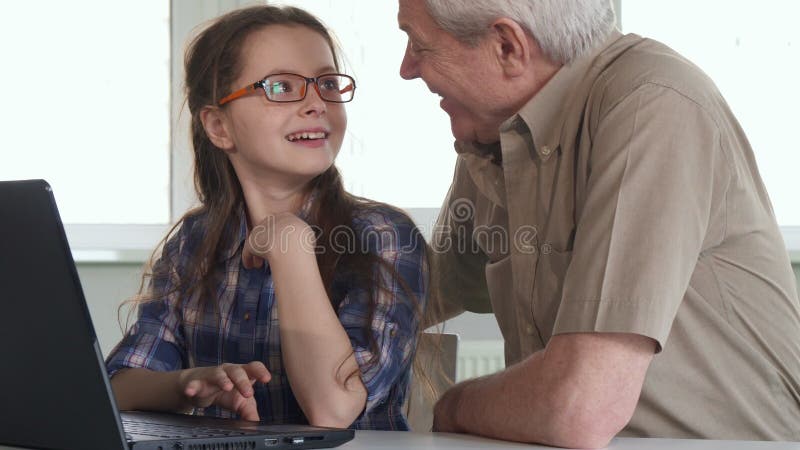 L'homme supérieur et sa petite-fille observent quelque chose sur l'ordinateur portable photographie stock libre de droits L'homme supérieur et sa petite-fille observent quelque chose sur l'ordinateur portable photographie stock libre de droits