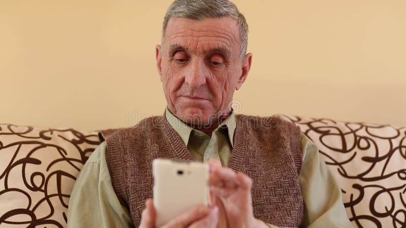 L'homme supérieur regarde et renverse par les photos dans son smartphone