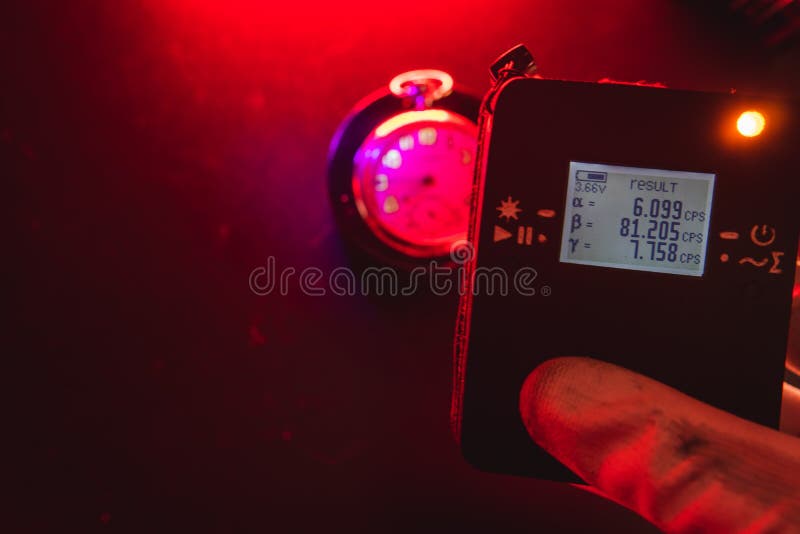 L'homme utilise un dosimètre de rayonnement radioactif à côté d'une vieille montre de poche avec une peinture fluorescente dangere images libres de droits