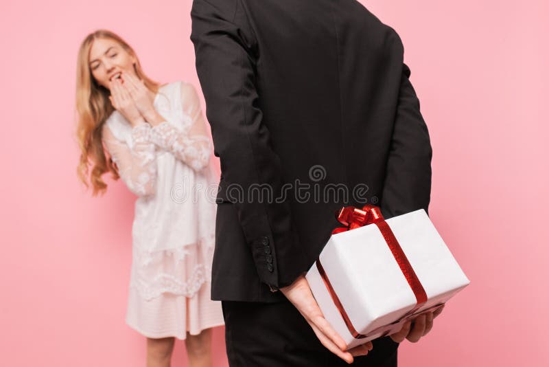 L'homme élégant dans un costume fait une surprise pour une femme, donne un bouquet des fleurs et d'une boîte avec un cadeau, sur photographie stock L'homme élégant dans un costume fait une surprise pour une femme, donne un bouquet des fleurs et d'une boîte avec un cadeau, sur photographie stock