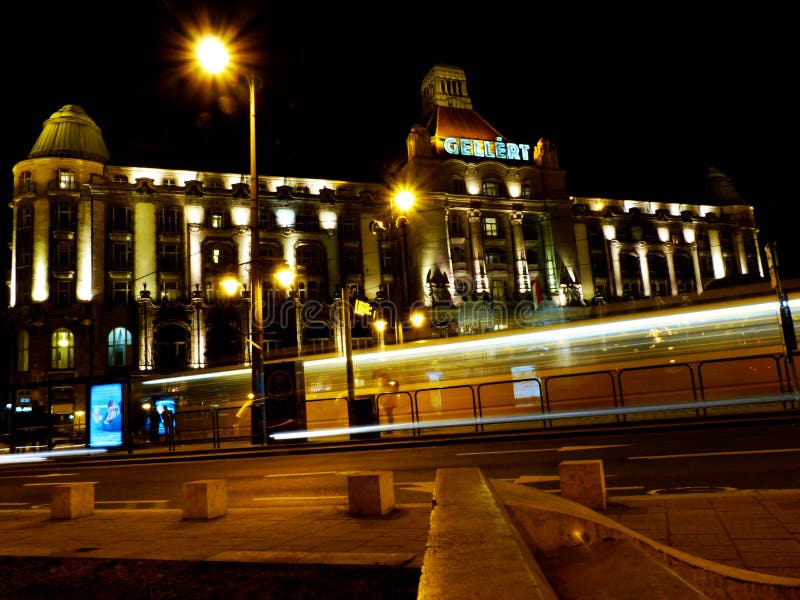 L'hotel di Gellert a Budapest con il tram giallo che passa vicino alla notte fotografie stock libere da diritti