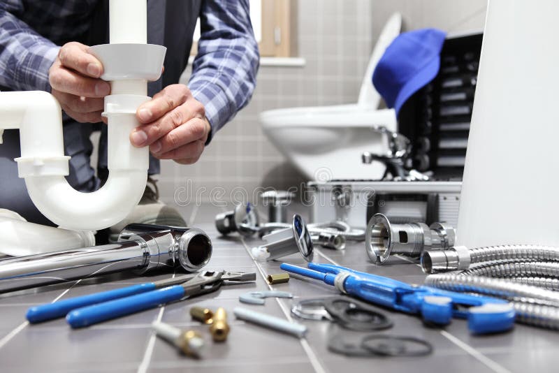 L'idraulico sul lavoro in un bagno, scandagliante il servizio di riparazione, monta