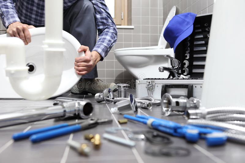 L'idraulico sul lavoro in un bagno, scandagliante il servizio di riparazione, monta