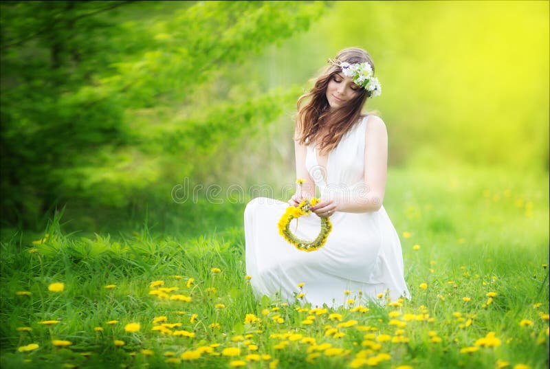 L'image de la jolie femme dans une robe blanche tisse la guirlande du dande images libres de droits L'image de la jolie femme dans une robe blanche tisse la guirlande du dande images libres de droits