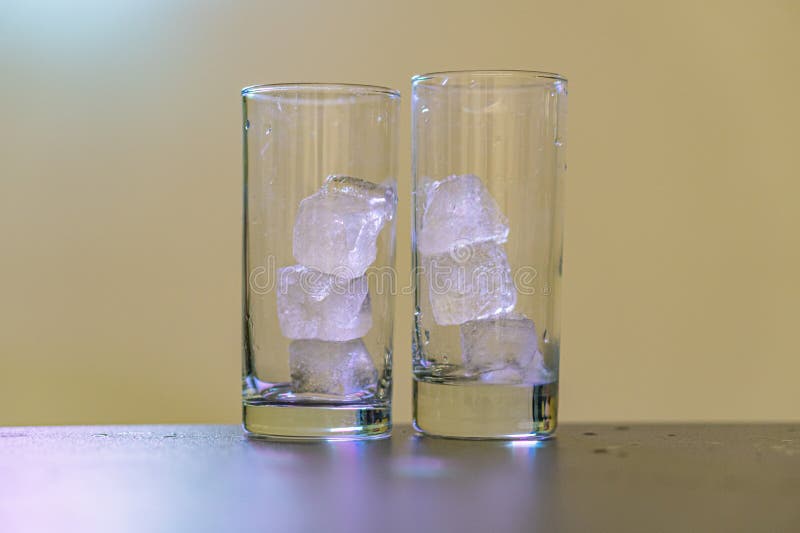 L'immagine mostra due bicchieri chiari pieni di cubetti di ghiaccio su una superficie nera elegante pronta per il vostro preferito fotografie stock
