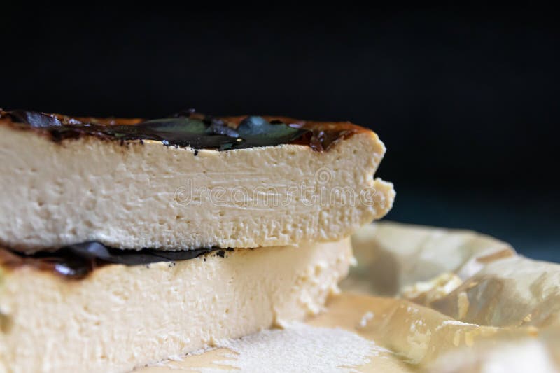 L'immagine mostra una fetta di formaggio basco bruciato su un piatto bianco. La cheesecake è marrone scuro e ha una trama cremosa fotografia stock