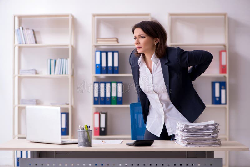 L'impiegato femminile di mezza et? che soffre nell'ufficio fotografia stock L'impiegato femminile di mezza et? che soffre nell'ufficio fotografia stock