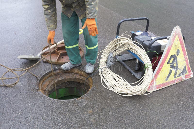 L'impiegato ha aperto la covata nella via per eliminare la situazione di emergenza fotografie stock libere da diritti L'impiegato ha aperto la covata nella via per eliminare la situazione di emergenza fotografie stock libere da diritti