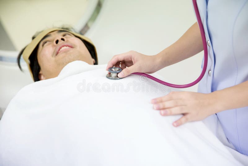 L'infirmière compte la fréquence cardiaque docteur à l'aide d'un stéthoscope pour écouter le coffre patient du ` s de l'homme vér photos stock L'infirmière compte la fréquence cardiaque docteur à l'aide d'un stéthoscope pour écouter le coffre patient du ` s de l'homme vér photos stock