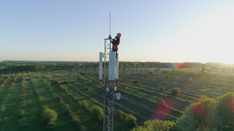 L'ingénieur avec l'instrument a relié une communication mobile sur la tour par radio de télécommunication sur le fond du ciel ble