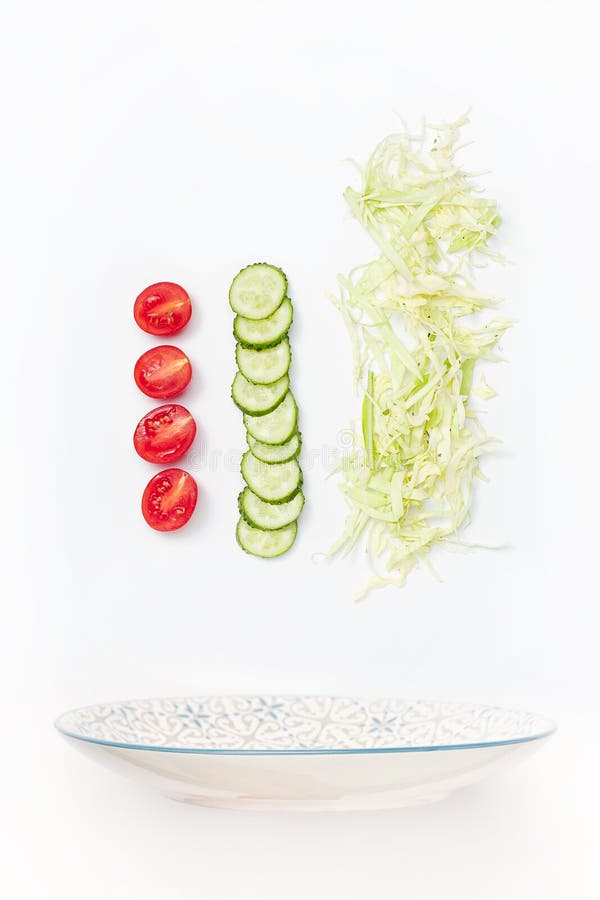 L'insalatiera in volo con le verdure: pomodoro, cetriolo, cavolo su fondo bianco fotografia stock libera da diritti L'insalatiera in volo con le verdure: pomodoro, cetriolo, cavolo su fondo bianco fotografia stock libera da diritti