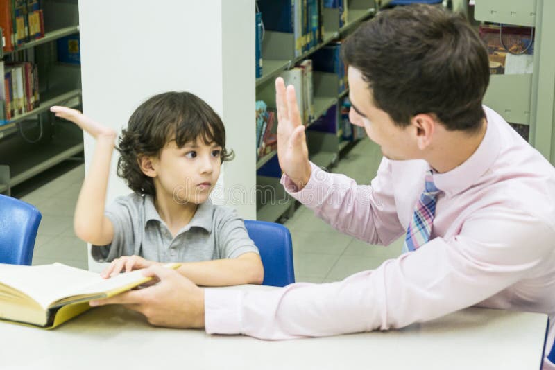 L'insegnante dell'uomo e lo studente del bambino imparano con il libro al backgro dello scaffale per libri fotografia stock libera da diritti L'insegnante dell'uomo e lo studente del bambino imparano con il libro al backgro dello scaffale per libri fotografia stock libera da diritti