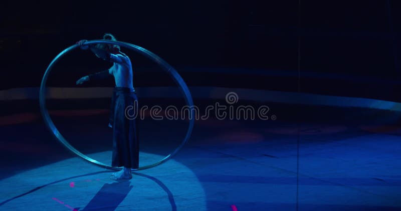 L'interprète de cirque se tient sur la scène sous les projecteurs tournant le cercle 4k clips vidéos