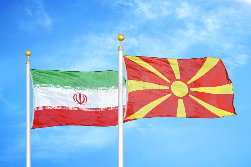 L'Iran et la Macédoine du nord deux drapeaux sur les mâts de drapeau et le fond bleu ciel nuageux