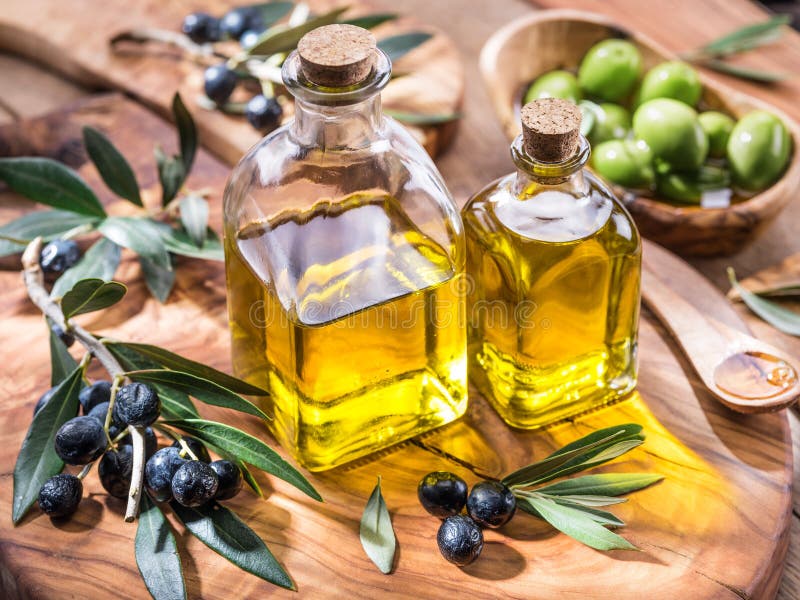 L'olio d'oliva e le bacche sono sul vassoio di legno verde oliva