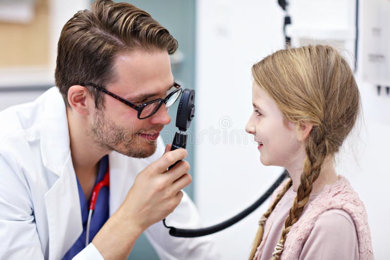 L'optometrista maschio del bambino esamina la vista della bambina fotografia stock