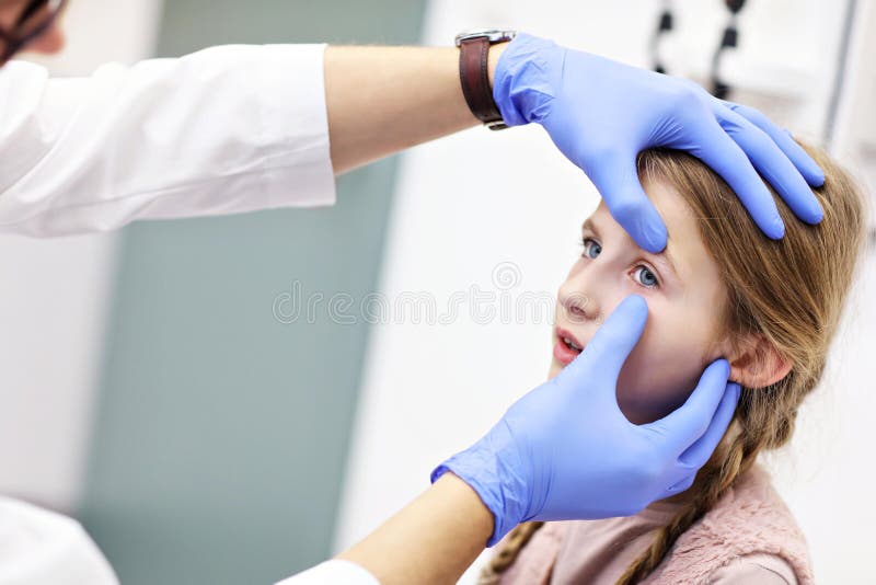 L'optometrista maschio del bambino esamina la vista della bambina immagine stock