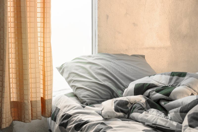 L'oreiller et la couverture de tartan avec la ride malpropre sur le lit dans l'orange soient photo stock L'oreiller et la couverture de tartan avec la ride malpropre sur le lit dans l'orange soient photo stock