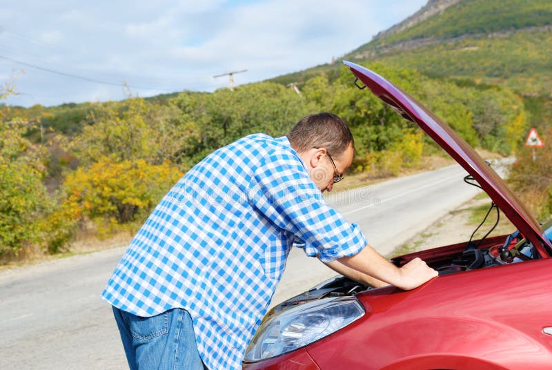 L'uomo adulto sta stando vicino alla sua automobile rotta immagini stock L'uomo adulto sta stando vicino alla sua automobile rotta immagini stock