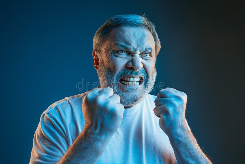 L'uomo arrabbiato emozionale senior che grida sul fondo blu dello studio fotografie stock libere da diritti L'uomo arrabbiato emozionale senior che grida sul fondo blu dello studio fotografie stock libere da diritti