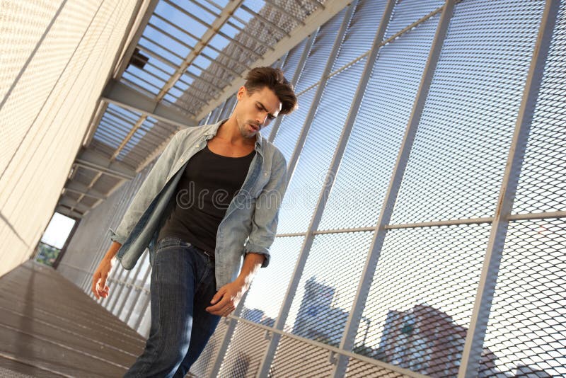 L'uomo bello ha vestito casuale in una posizione grungy fotografia stock L'uomo bello ha vestito casuale in una posizione grungy fotografia stock