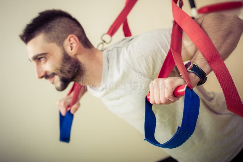 L'uomo che adatto fare spinge aumenta le armi di addestramento con le cinghie di forma fisica immagini stock L'uomo che adatto fare spinge aumenta le armi di addestramento con le cinghie di forma fisica immagini stock