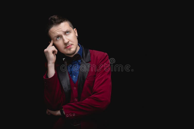 L'uomo con le orecchie piercose in giacca rossa analizza la situazione con attenzione. fondo isolato nero fotografie stock