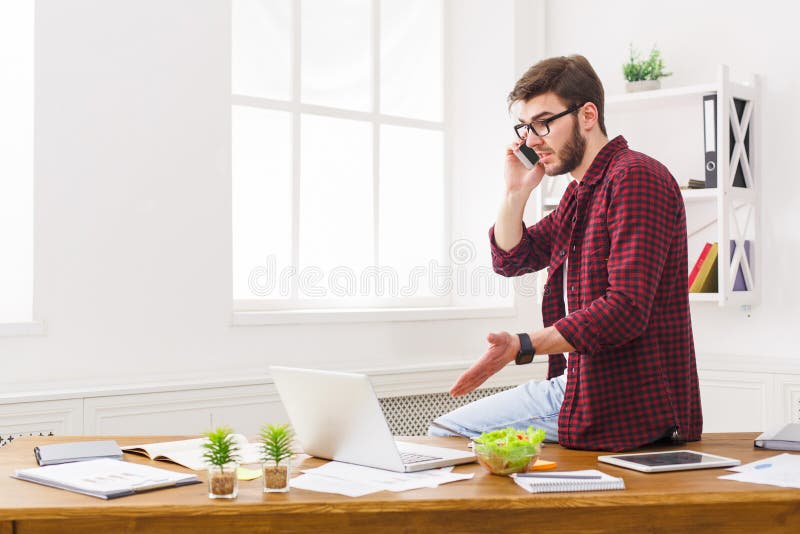 L'uomo d'affari concentrato giovani ha letto i documenti in ufficio bianco moderno fotografia stock L'uomo d'affari concentrato giovani ha letto i documenti in ufficio bianco moderno fotografia stock