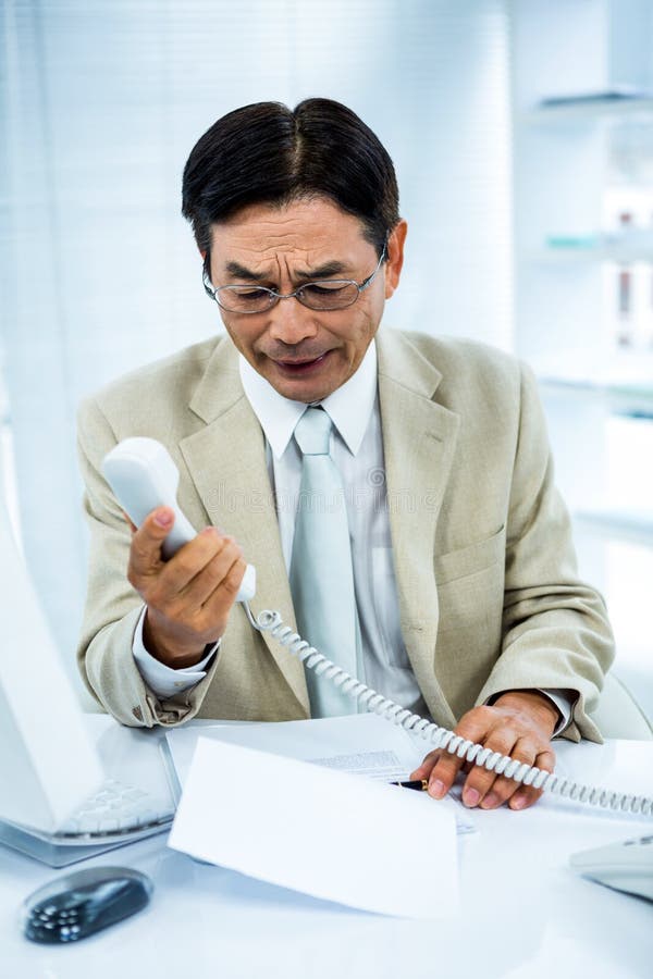 L'uomo d'affari frustrato guarda il suo telefono fotografie stock libere da diritti L'uomo d'affari frustrato guarda il suo telefono fotografie stock libere da diritti