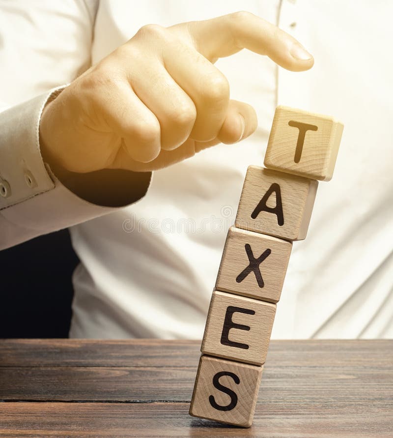 Businessman removes wooden blocks with the word Taxes. The concept of tax payment for housing and property. Income / goods tax. Avoidance. Burden Taxation. GST. Business and Finance. Selective . Businessman removes wooden blocks with the word Taxes. The concept of tax payment for housing and property. Income / goods tax. Avoidance. Burden Taxation. GST. Business and Finance. Selective