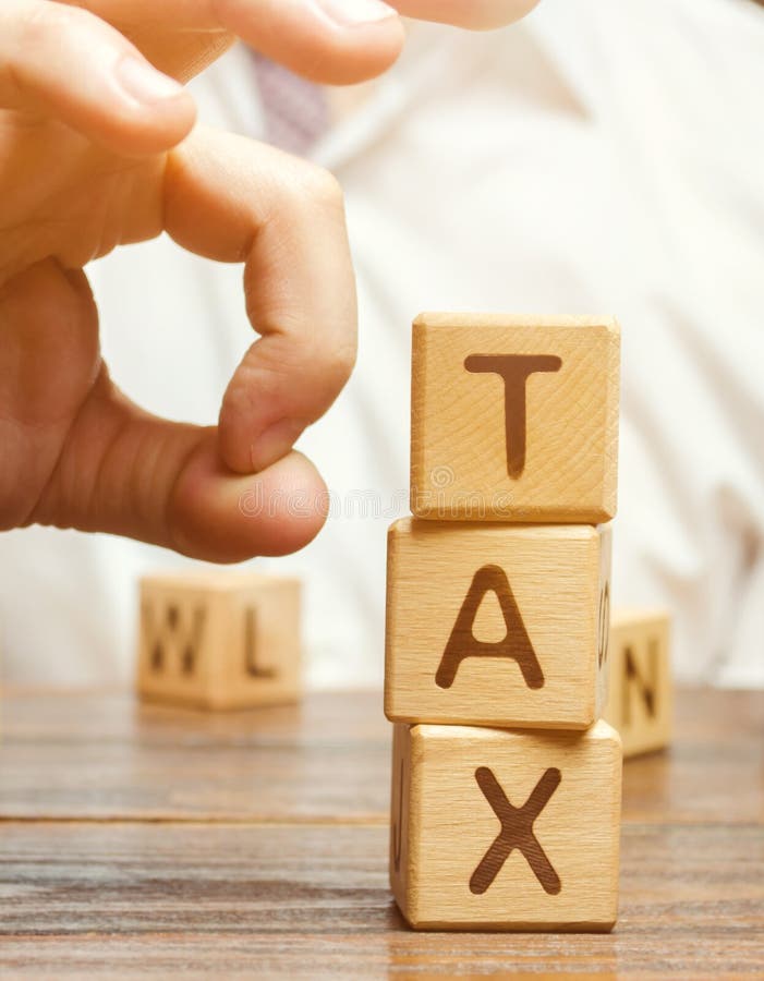 Businessman removes wooden blocks with the word Tax. The concept of reducing the tax burden. Tax avoidance. Costs and expenses of the business. Taxation. Pay off debt. Freedom from illegal taxes. Businessman removes wooden blocks with the word Tax. The concept of reducing the tax burden. Tax avoidance. Costs and expenses of the business. Taxation. Pay off debt. Freedom from illegal taxes