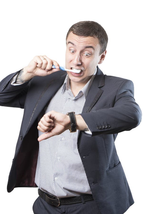 L'uomo d'affari è in ritardo Pulisce i suoi denti ed esamina il suo orologio nel panico immagini stock libere da diritti L'uomo d'affari è in ritardo Pulisce i suoi denti ed esamina il suo orologio nel panico immagini stock libere da diritti