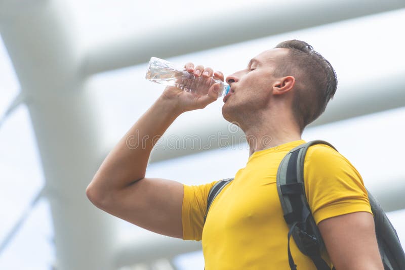 l'uomo di sport nel giallo è l'acqua della bevanda in città all'aperto fotografie stock libere da diritti l'uomo di sport nel giallo è l'acqua della bevanda in città all'aperto fotografie stock libere da diritti