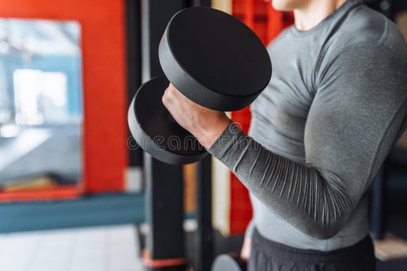 L'uomo di sport solleva i pesi nell'addestramento nella palestra, primo piano delle mani fotografia stock L'uomo di sport solleva i pesi nell'addestramento nella palestra, primo piano delle mani fotografia stock