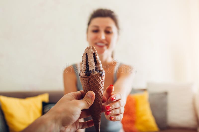 L'uomo dà il gelato al cioccolato in cono alla sua amica a casa Fine in su immagine stock L'uomo dà il gelato al cioccolato in cono alla sua amica a casa Fine in su immagine stock