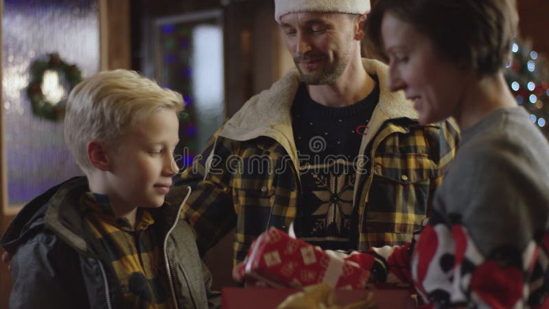 L'uomo ed il ragazzino dà i regali di Natale alla donna e l'uomo la bacia