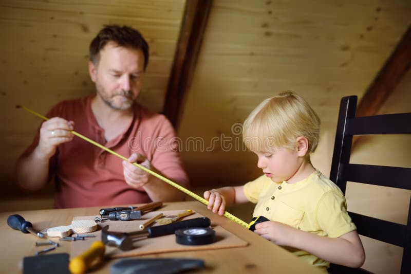 L'uomo ed il ragazzino maturi fanno insieme un giocattolo di legno Il padre impara il suo lavoro del figlio con gli strumenti Ist immagini stock libere da diritti L'uomo ed il ragazzino maturi fanno insieme un giocattolo di legno Il padre impara il suo lavoro del figlio con gli strumenti Ist immagini stock libere da diritti