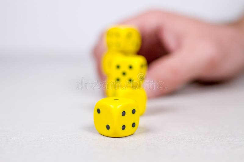 L'uomo equipaggia la mano che impila sui dadi gialli nei precedenti fotografie stock L'uomo equipaggia la mano che impila sui dadi gialli nei precedenti fotografie stock