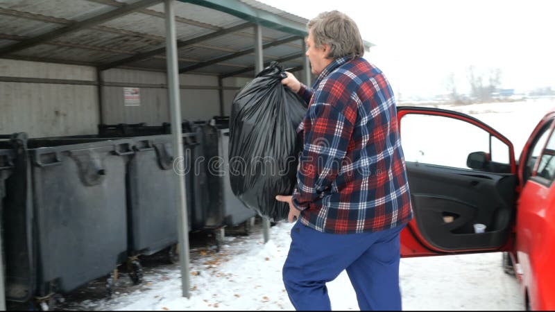 L'uomo getta una borsa nera con di immondizia nei rifiuti