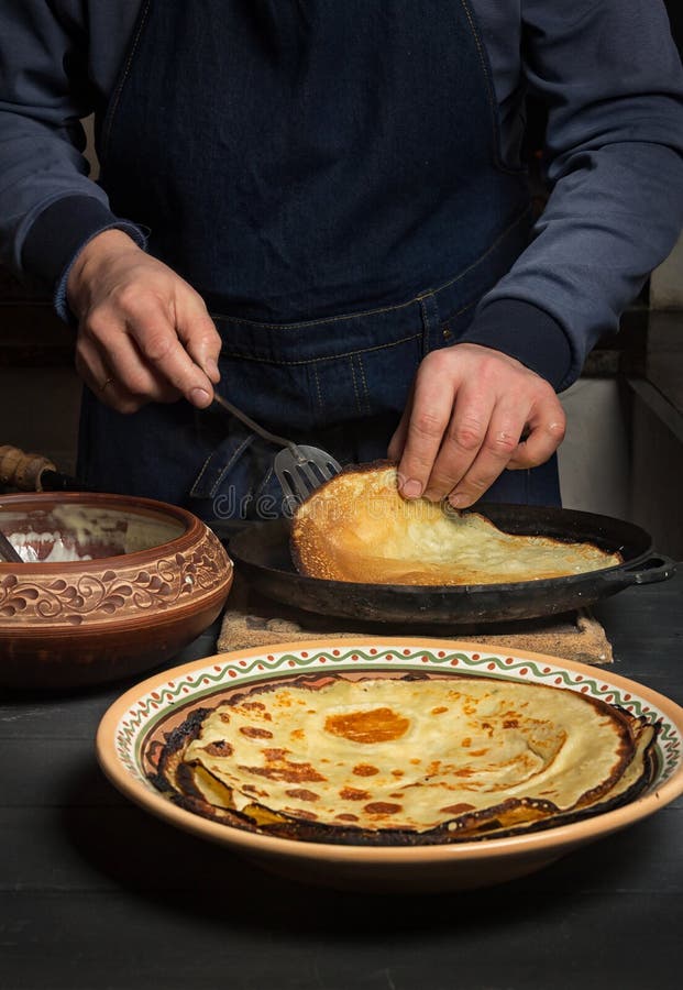 L'uomo Gira Il Pancake Sulla Pentola Bei Pancake Su Una Zolla Fotografia  Stock - Immagine di caldo, crepa: 135789228