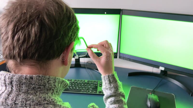 L'uomo lavora in ufficio in due computer, mentre la chiave chroma verde porta via gli occhiali che guardano i capelli rossi della