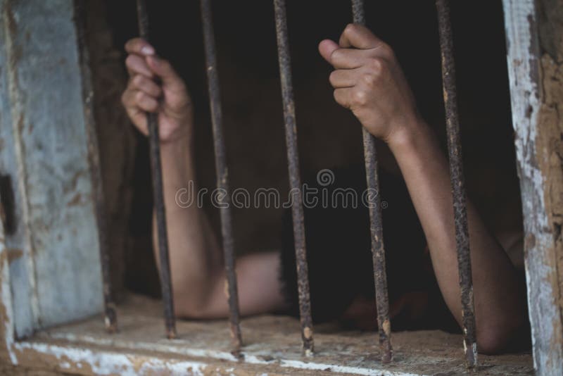 L'uomo in mani della prigione delle barre d'acciaio della prigione della gabbia della tenuta indietro, prigionieri maschii è stat